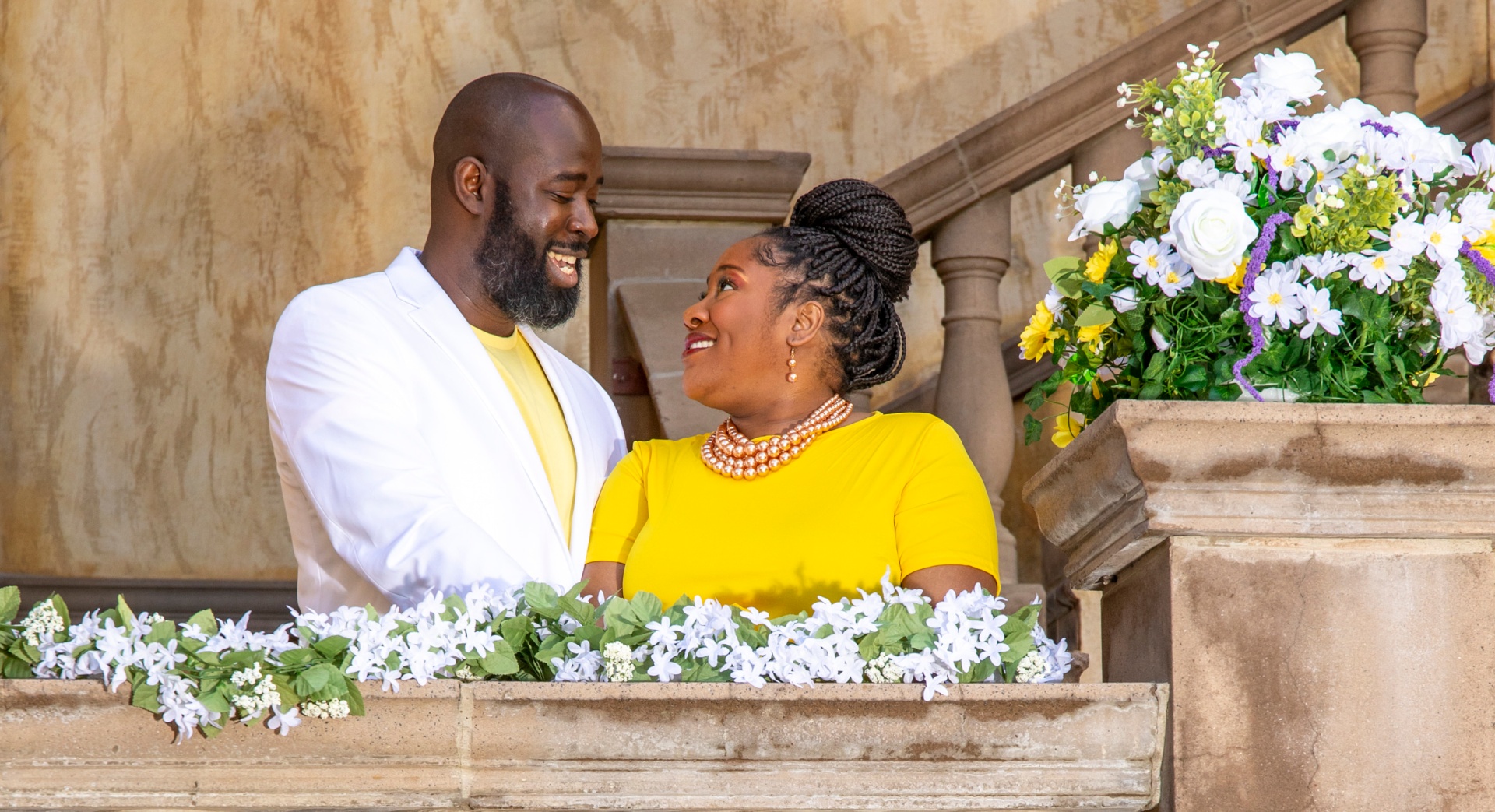 Boris and Marion smiling at each other beside a floral arrangement